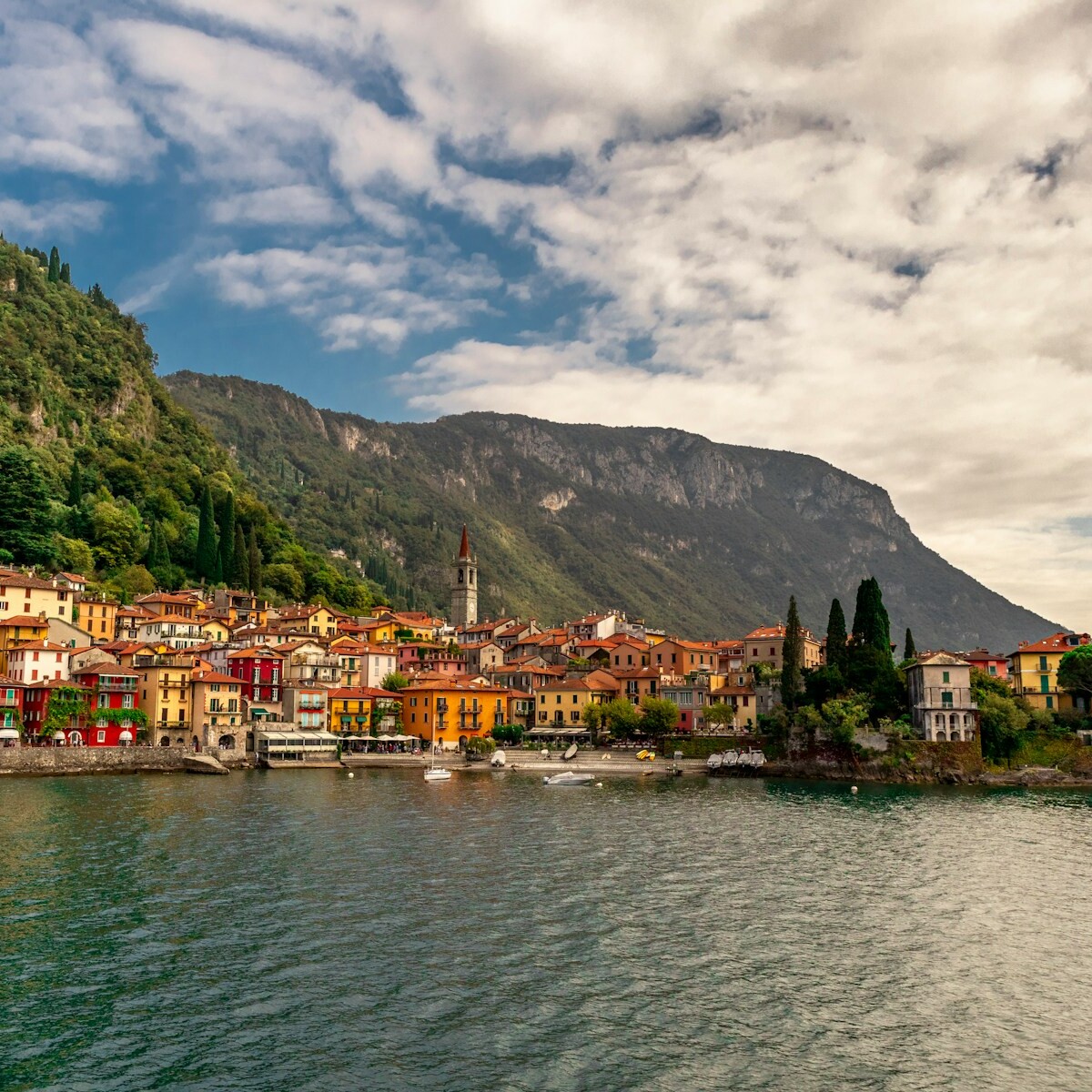 houses near body of water under cloudy sky during daytime
