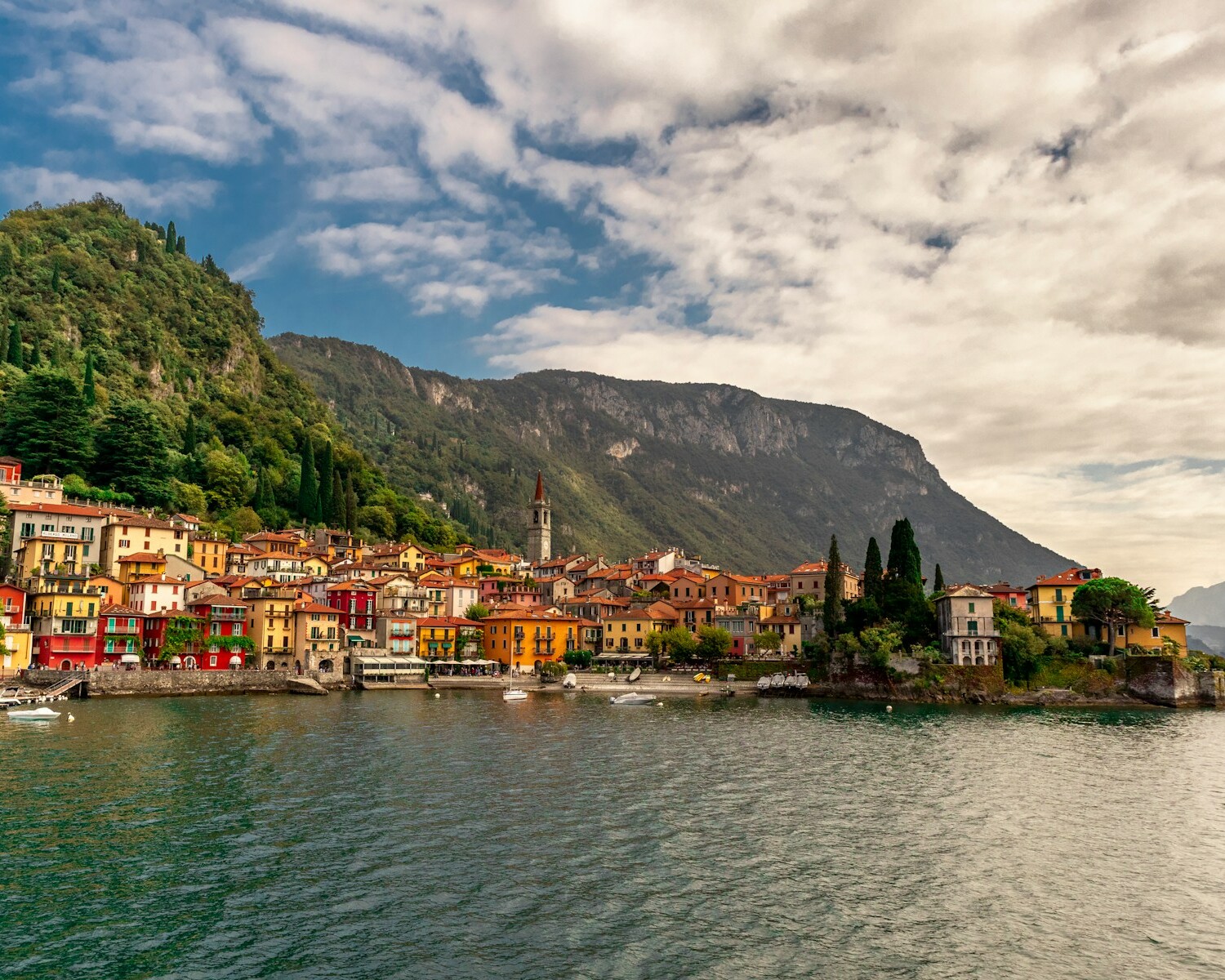 houses near body of water under cloudy sky during daytime